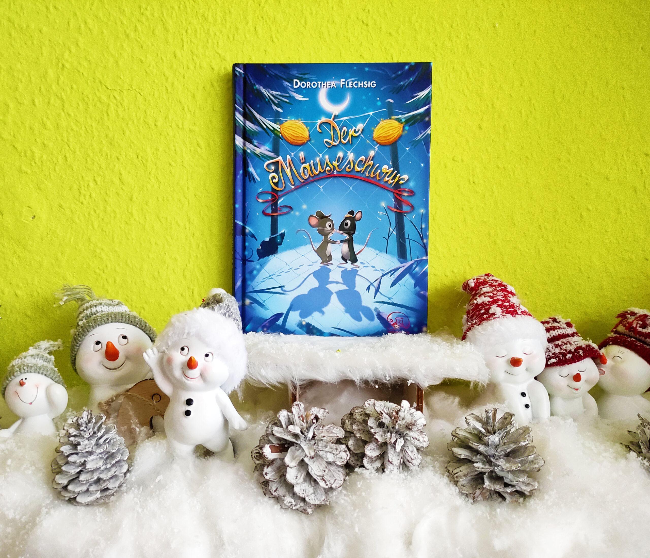Das Buch Der Mäuseschwur steht auf einem Schlitten, umringt von Schneemännern, Tannenzapfen und Watte.